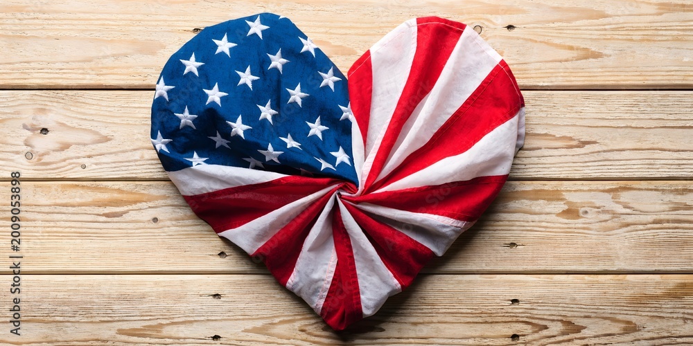 Obraz premium Heart Shaped American Flag Fabric on Wooden Background Representing Love for Country Patriotism and Independence Day Concept