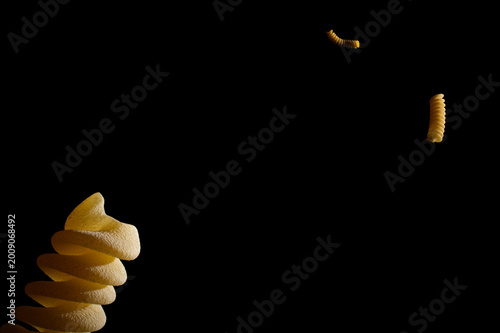 Floating Fusilli pasta shapes in deep black space, cosmic food metaphor.