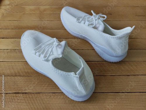 White fabric sneakers on the wooden background