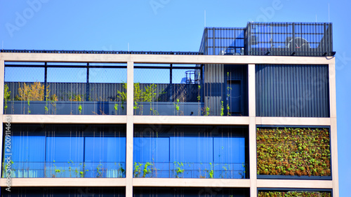 Sustainable glass office building with trees for reducing carbon dioxide. Eco-friendly building in modern city. Office with green environment. Corporate building reduce CO2.