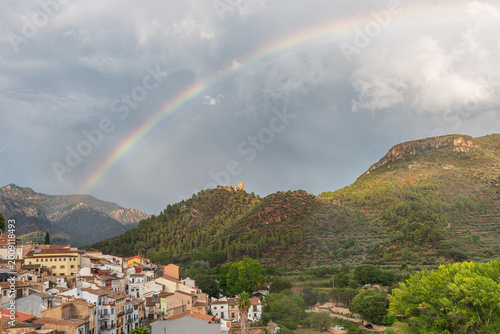 Small mountain village with a stormy sky and a large rainbow.