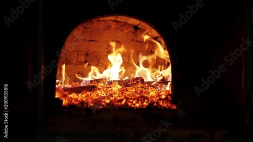 urning fire inside a traditional brick wood oven with glowing embers and baking bread.