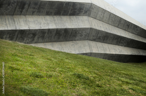 Abstract brutalist concrete building with geometric lines and grass slope