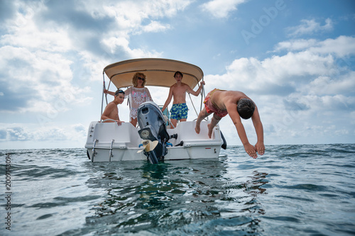 Konstfotografi Middle aged mother with her three teenage sons on a motorboat during summer vaca