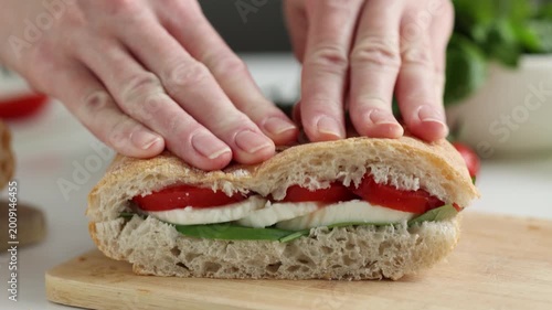 Woman hands cooking healthy panini sandwich with lettuce, mozzarella cheese and tomatoes. Italian style panini sandwich