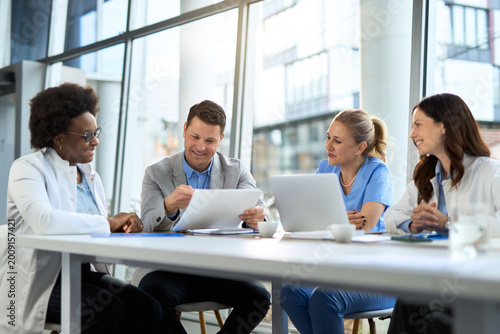 Fotografie Happy mid adult businessman having a meeting with group of doctors at the clinic