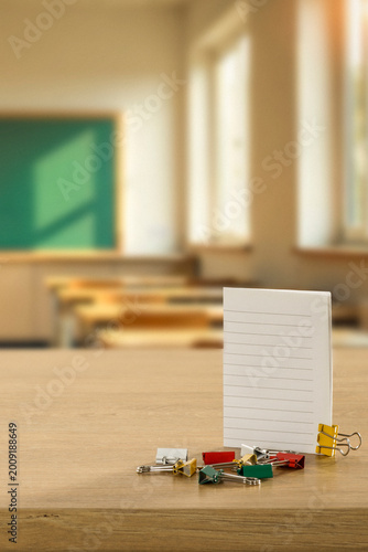 School and office items arranged on desk or classroom bench with clean copy space for product placement. Blurred classroom interior enhances the concept of education, studying and office work.
