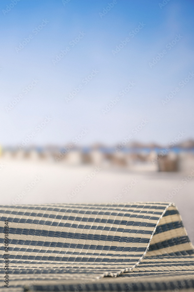 Fototapeta premium Minimal summer composition featuring clean sandy beach with empty copy space for product placement. Rocky coastline meets the sea under bright blue sky, creating natural and scenic atmosphere.
