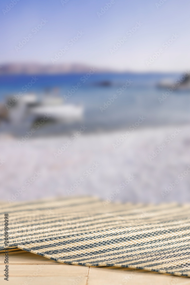 Fototapeta premium Minimal summer composition featuring clean sandy beach with empty copy space for product placement. Rocky coastline meets the sea under bright blue sky, creating natural and scenic atmosphere.