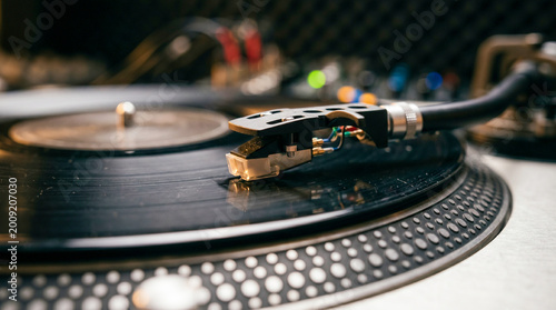 Close-up of a professional DJ turntable needle playing a vinyl record in a recording studio.