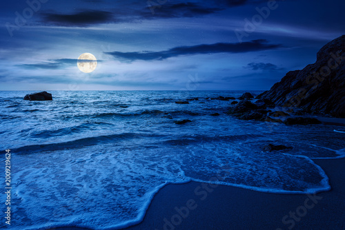 mysterious sandy sea beach at night. full moon over scene on cold summer vacation season. beautiful view of waves washing the sand. generic image of seascape and sky for advertising background
