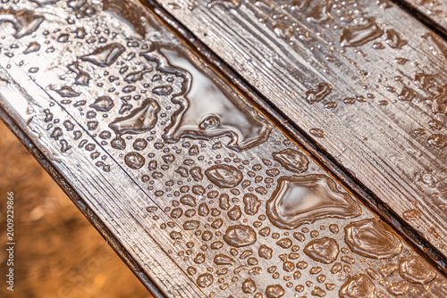 Photos Raindrops forming diverse patterns on a wet wooden table, creating a textured ba