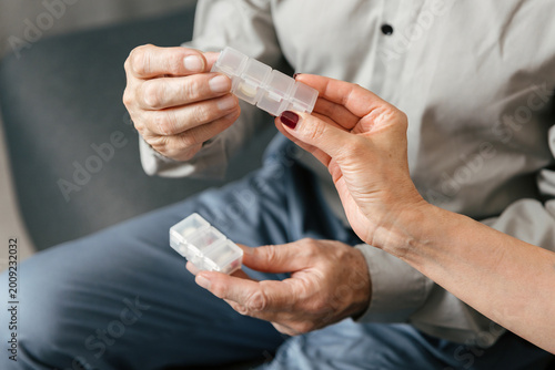 Elderly patient takes medication with assistance during a home care visit
