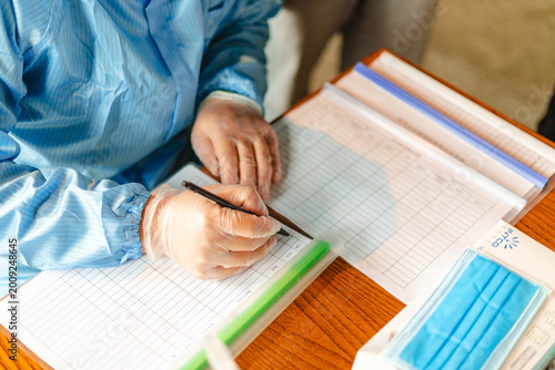 Healthcare worker completing registration form in protective clothing with face masks