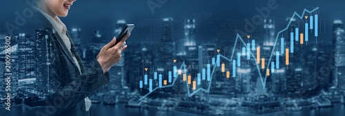 Foto A businesswoman interacts with her smartphone while overlooking a digital financial chart at night, highlighting market trends and investment insights against a city skyline
