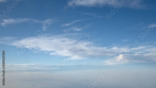 Bild auf Leinwand Fluffy white stratus and altostratus clouds on a blue sky, seen from an airplane