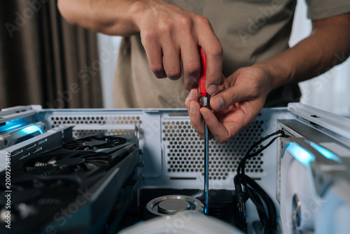 Fotografie Close-up of technician hands maintaining and upgrading a personal computer, assembling internal hardware components with screwdriver, performing service and repair on desktop pc during it support