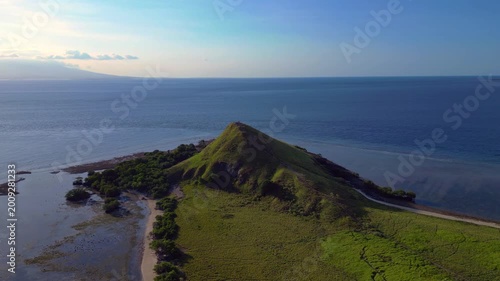Pulau kenawa island hiking hill with clear ocean. Smooth aerial view drone