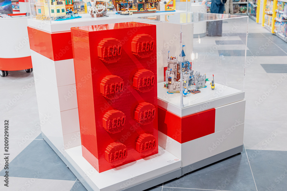 Fototapeta premium 19 October 2025, Belgrade, Serbia: Red oversized LEGO brick and intricate castle model on display in a modern retail store, inviting play and creativity