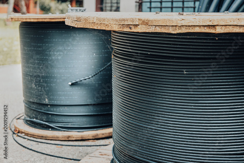 Two large wooden spools holding black fiber optic cables, representing internet infrastructure and telecommunications deployment