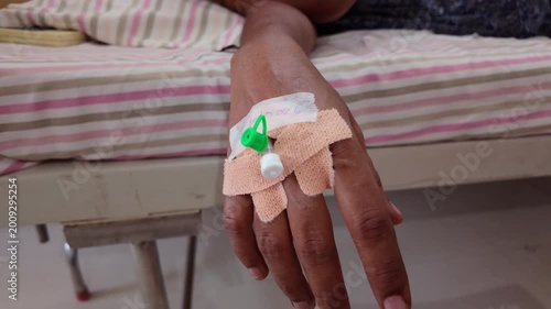 Patient receiving treatment on a bed with an IV line attached to the hand during hospital visit in the afternoon