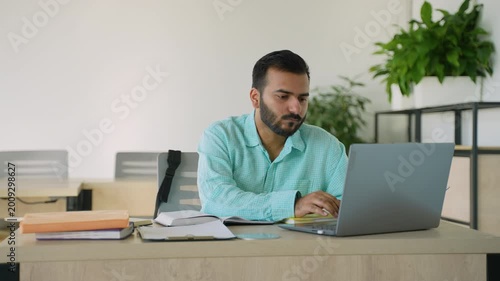 Focused Indian businessman working on laptop at office desk