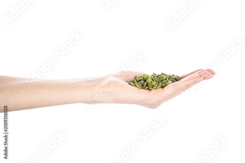 Pumpkin seeds' kernel in woman hands isolated on white background.