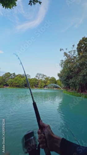 Vertical video. Hand Holding Strongly Bent Fishing Rod Over Lake Water First Person View Wide Angle Intense Fight with Large Fish Outdoor Angling Sport Action