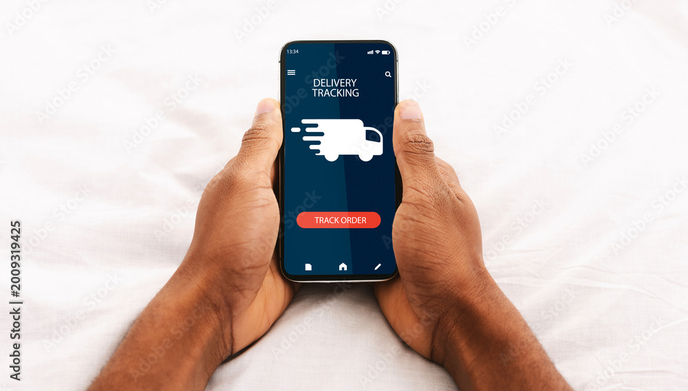Naklejka premium Track Your Order Online. Point of view of black man holding and using his smartphone with delivery tracking service application, checking status of domestic and international shipments via internet