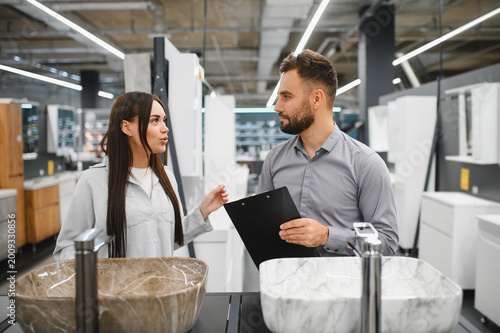 Woman buying bathroom sink, discussing with seller