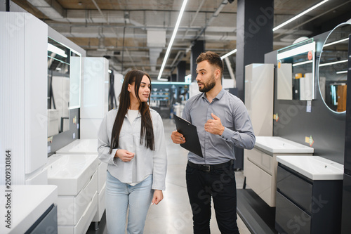 Salesman assisting female customer in hardware store showroom