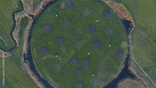 Aerial view of the LOFAR superterp radio telescope station with its circular green mound and geometric antenna arrays surrounded by water channels in Buinen, Drenthe, Netherlands.