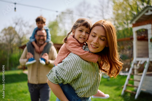 Canvastavla Happy mother piggybacking her daughter while enjoying in family day in nature