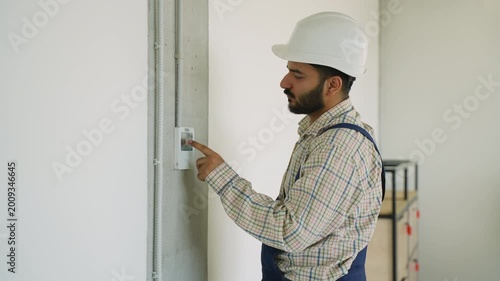 Male technician adjusting a smart home thermostat on the wall