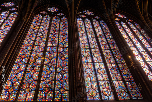 Tableau sur toile Interior view of medieval Gothic cathedral featuring towering stained-glass windows that fill nave with colored light, detailed biblical iconography