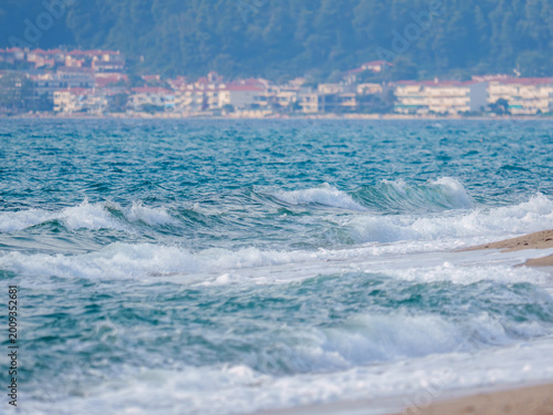 Фотография Breaking Sea Waves on Sandy Beach with Coastal Town Background