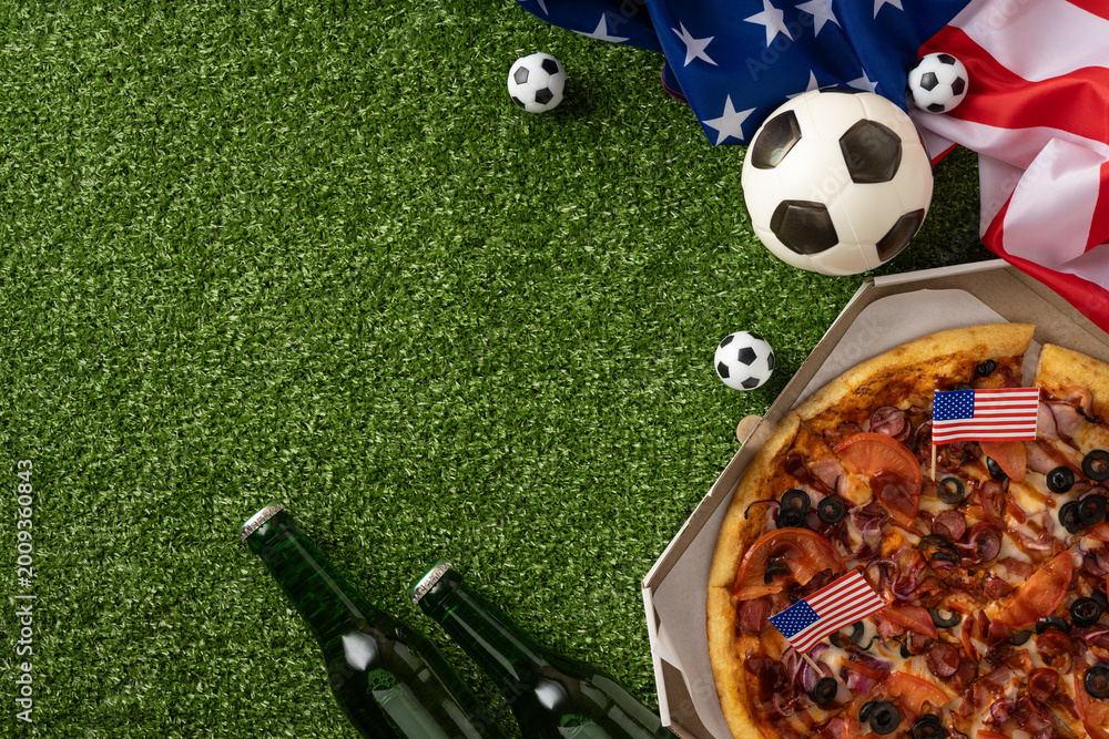 Naklejka premium Football championship party with pizza, American flag, soccer ball and beer on green turf