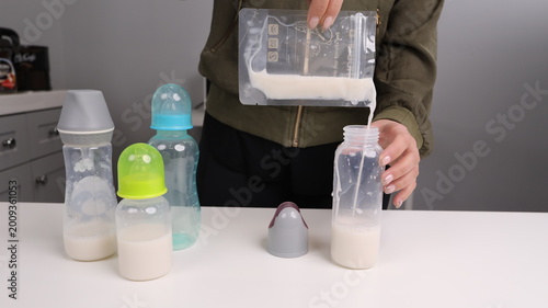 Fotografía Person pouring stored breast milk from a plastic storage bag into a baby bottle, preparation for infant feeding