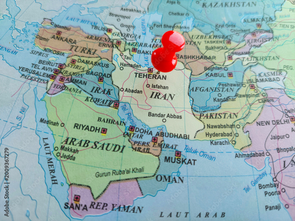 Obraz premium Red pushpin, pinned near Tehran on world map in Indonesian language, highlighting Iran among other countries in the Middle East, for geography, geopolitics, international relations, borders concepts.