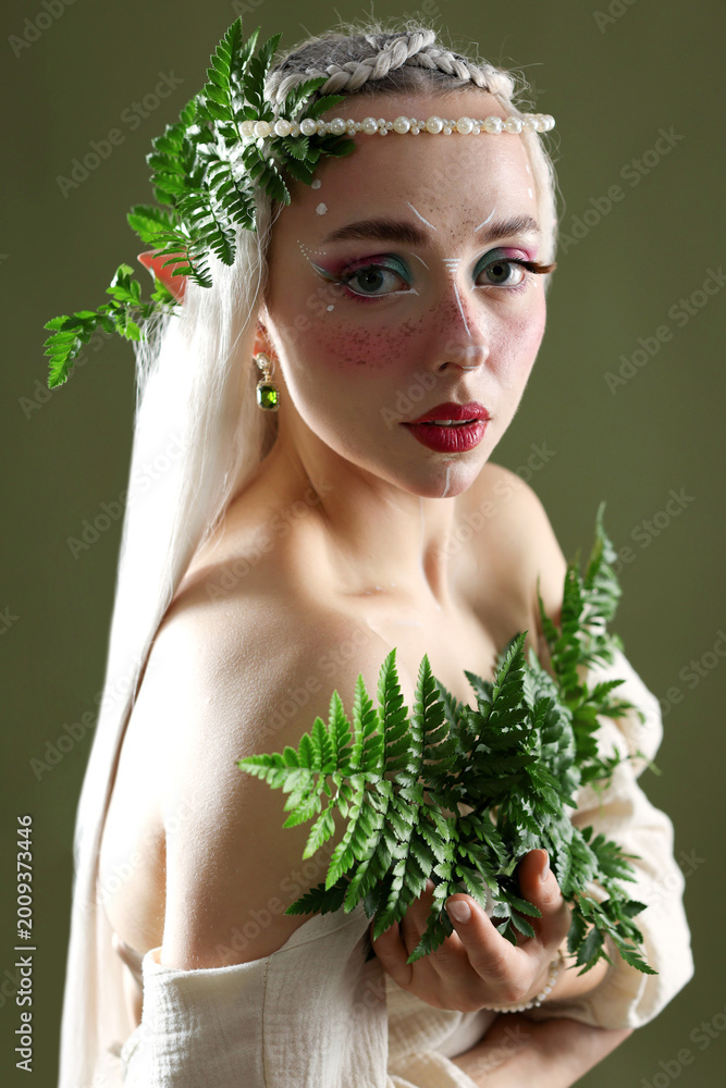 Fototapeta premium Beautiful elf girl with floral decor on dark olive background