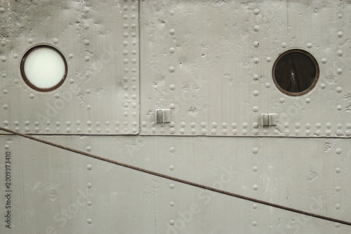 Surface view of ship’s hull with rivets, portals and cable
