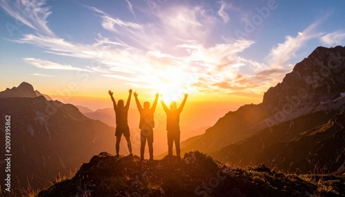 Three friends standing with raised arms on mountain peak at sunset, representing teamwork, success, achievement, victory, and reaching goals together