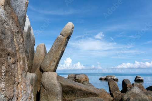 Obraz na plátně Granite rock formation resembling a phallic shape rising against blue sky with clouds on tropical island coastal landscape