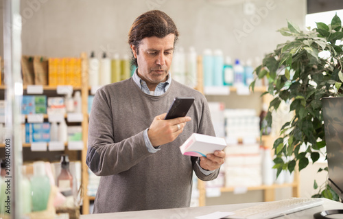 Φωτογραφία Adult man buyer scanning qr code for box of pills in pharmacy