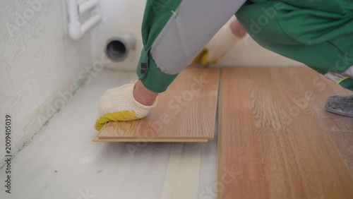Professional worker installing wooden laminate flooring. Home improvement and construction concept