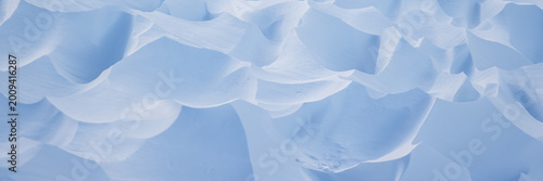 Snow texture. Wind sculpted patterns on snow surface. Wind in the tundra and in the mountains on the surface of the snow sculpts patterns and ridges. Arctic, Polar region. Winter panoramic background.