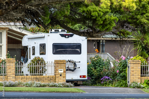 Motorhome and caravan parked on driveway in front of residential house in suburban Australia. Road trip lifestyle, recreational vehicle storage and Australian travel culture