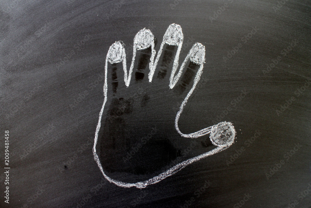 Naklejka premium Outline of a Human Hand Traced in White Chalk on a Blackboard