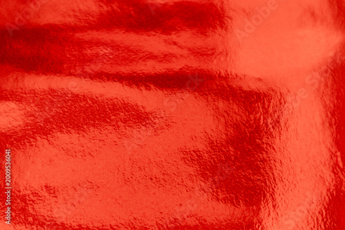 Shiny Red foil texture background with uneven surface. Abstract red orange foil background, metal texture wallpaper