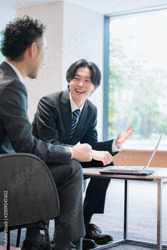 オフィスラウンジで商談する営業社員の法人提案ビジネスイメージ　不動産や士業などの少し堅い仕事のイメージ